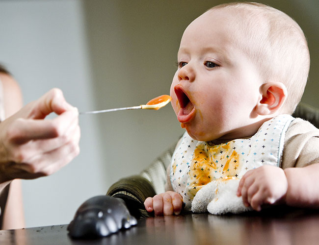Baby being spoon fed baby food at 4 months.