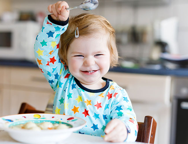 18-24 month eating soup with a spoon.